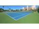 Two tennis courts with blue surface and green surrounding at 7300 Sun Island S Dr # 1102, South Pasadena, FL 33707