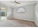 Bright bedroom with carpet, an arched window, and sliding doors to the pool at 500 Waterford W Cir, Tarpon Springs, FL 34688