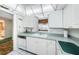 White cabinets, counter, and backsplash with vintage wallpaper. Dishwasher and view into living area at 300 Woodette Dr # 202B, Dunedin, FL 34698