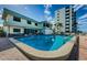 Community pool area with lounge chairs and well-manicured building exterior under a sunny sky at 300 Woodette Dr # 202B, Dunedin, FL 34698