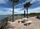 Waterfront patio with seating and palm trees at 100 Bluff View Dr # 208B, Belleair Bluffs, FL 33770
