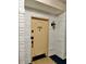 Beige front door entrance to unit 208, with white brick wall and a light fixture at 100 Bluff View Dr # 208B, Belleair Bluffs, FL 33770