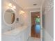 Double sink bathroom with marble countertops, and view into bedroom at 100 Bluff View Dr # 208B, Belleair Bluffs, FL 33770