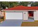 House exterior showcasing a red tile roof, white garage door, and red front door at 2502 Indigo Dr, Dunedin, FL 34698