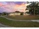 Charming home with a well-maintained lawn, mature trees, and colorful sunset at 2502 Indigo Dr, Dunedin, FL 34698