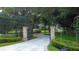 Gated entrance to a property with a long driveway and lush landscaping at 2901 Leprechaun Ln, Palm Harbor, FL 34683