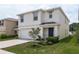 Two-story house with a white exterior, two-car garage, and landscaped yard at 36478 Spanish Rose Dr, Dade City, FL 33525