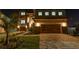 Stunning two-story home featuring stone accents, a paver driveway, and a well-manicured lawn at night at 2121 Bayou Grande Ne Blvd, St Petersburg, FL 33703