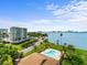 Aerial view showcasing the waterfront condo building with a pool, lush landscaping, and water views at 100 Oakmont Ln # 301, Belleair, FL 33756