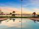 Community swimming pool with clear blue water and views of the bay and palm trees at sunset at 100 Oakmont Ln # 301, Belleair, FL 33756