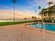 Community pool features lush landscaping, waterfront views, and lounge chairs with umbrellas at 100 Oakmont Ln # 301, Belleair, FL 33756