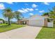 Single story home with a two-car garage and palm trees at 12218 Buttonwood Row, Hudson, FL 34667