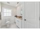 Bright bathroom features a toilet, vanity with granite countertop, white cabinetry and a white paneled wall at 106 19Th Ave, St Pete Beach, FL 33706