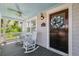 Inviting front porch with rocking chairs, wood floors, and a dark wood front door with wreath at 106 19Th Ave, St Pete Beach, FL 33706