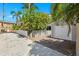 One car garage in a gravel driveway with a white fence surrounding it and tropical greenery in the background at 106 19Th Ave, St Pete Beach, FL 33706