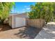 Home's single car garage on a gravel driveway, surrounded by a wooden fence and lush tropical landscaping at 106 19Th Ave, St Pete Beach, FL 33706