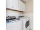 White laundry room features a modern washer, dryer, white cabinets and beadboard walls at 106 19Th Ave, St Pete Beach, FL 33706