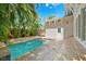 Backyard pool surrounded by stone patio, tropical foliage, privacy fence, and gray home exterior at 106 19Th Ave, St Pete Beach, FL 33706