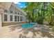 Backyard pool surrounded by stone patio, tropical foliage and a gray home exterior at 106 19Th Ave, St Pete Beach, FL 33706