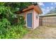 Small backyard shed with a gray door, surrounded by lush vegetation at 1618 Valencia St, Clearwater, FL 33756