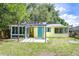 Charming yellow home with a bright blue door, screened-in porch and partially fenced yard at 5210 Newton S Ave, Gulfport, FL 33707