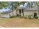 Home exterior featuring mature trees, manicured lawn, and a modern front entryway with large windows at 5841 Bay Pines Lakes Blvd, St Petersburg, FL 33708