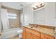 Bathroom showcasing a granite countertop vanity, a bathtub, and a tiled shower area with a window for natural light at 1740 51St N St, St Petersburg, FL 33710