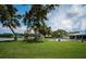 Expansive waterfront lawn with mature trees, patio with outdoor furniture, and private pool at 4751 Baywood Point S Dr, Gulfport, FL 33711