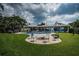 The spacious backyard has green grass, a patio with a fire pit, a pool, and beautiful tropical landscaping at 4751 Baywood Point S Dr, Gulfport, FL 33711