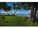 Waterfront backyard with green lawn, trees, a concrete patio, and a view of the water at 4751 Baywood Point S Dr, Gulfport, FL 33711