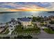 Stunning aerial view of waterfront estate with lush landscaping, circular driveway, and breathtaking sunset backdrop at 774 Nina Dr, Tierra Verde, FL 33715