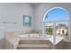 Bathroom with soaking tub under a large arched window, providing natural light and a view to the outdoors at 774 Nina Dr, Tierra Verde, FL 33715