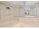 An opulent bathroom offers a glass shower and an elevated jacuzzi tub next to a large arched window at 774 Nina Dr, Tierra Verde, FL 33715