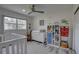 Bedroom includes a white crib, dresser, shelves, ceiling fan, and wood-look vinyl floors at 7809 Alafia Dr, Riverview, FL 33578