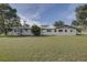 Rear exterior view of the house showing the metal roof, fresh white paint, and large grassy lawn at 7809 Alafia Dr, Riverview, FL 33578
