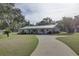 Charming home exterior featuring a covered porch, metal roof, and lush green lawn leading to a paved driveway at 7809 Alafia Dr, Riverview, FL 33578