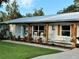 Welcoming front porch featuring a swing, rocking chairs, wood columns, and landscaped garden beds at 7809 Alafia Dr, Riverview, FL 33578
