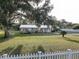 Quaint home with a well-manicured front yard, white picket fence, and mature oak tree at 7809 Alafia Dr, Riverview, FL 33578