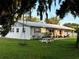 White brick ranch house with metal roof, front porch, and a large yard with a playset at 7809 Alafia Dr, Riverview, FL 33578
