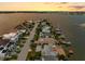 An aerial view of a waterfront property at sunset, showing the house and surrounding neighborhood at 11220 9Th E St, Treasure Island, FL 33706