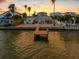 An aerial view of a waterfront home with a private dock, beautiful sunset and neighboring houses at 11220 9Th E St, Treasure Island, FL 33706