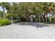 Gravel parking area with mature trees and a house in the background at 516 Gulf Blvd, Indian Rocks Beach, FL 33785