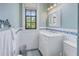 Clean bathroom with white vanity, tile floor, and a window overlooking lush greenery at 516 Gulf Blvd, Indian Rocks Beach, FL 33785