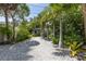 Backyard with gravel ground cover, lush tropical foliage, and a glimpse of the house at 516 Gulf Blvd, Indian Rocks Beach, FL 33785