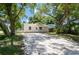 Tan single-story house with a gravel driveway and large shade trees at 4000 7Th N Ave, St Petersburg, FL 33713