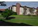 Attractive condo building with a brick chimney, lush greenery, and mature trees at 3455 Countryside Blvd # 15, Clearwater, FL 33761