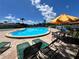 Community pool with lounge chairs and umbrella at 182 114Th Ne Ter # 182, St Petersburg, FL 33716