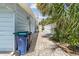 Side yard with brick pavers and trash receptacles at 18053 2Nd E St, Redington Shores, FL 33708