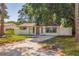 Well-maintained home with a tree-lined front yard and gated driveway at 135 Se Monroe N Cir, St Petersburg, FL 33703