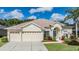 House exterior featuring a three-car garage, manicured lawn, and attractive landscaping at 22531 Eagles Watch Dr, Land O Lakes, FL 34639